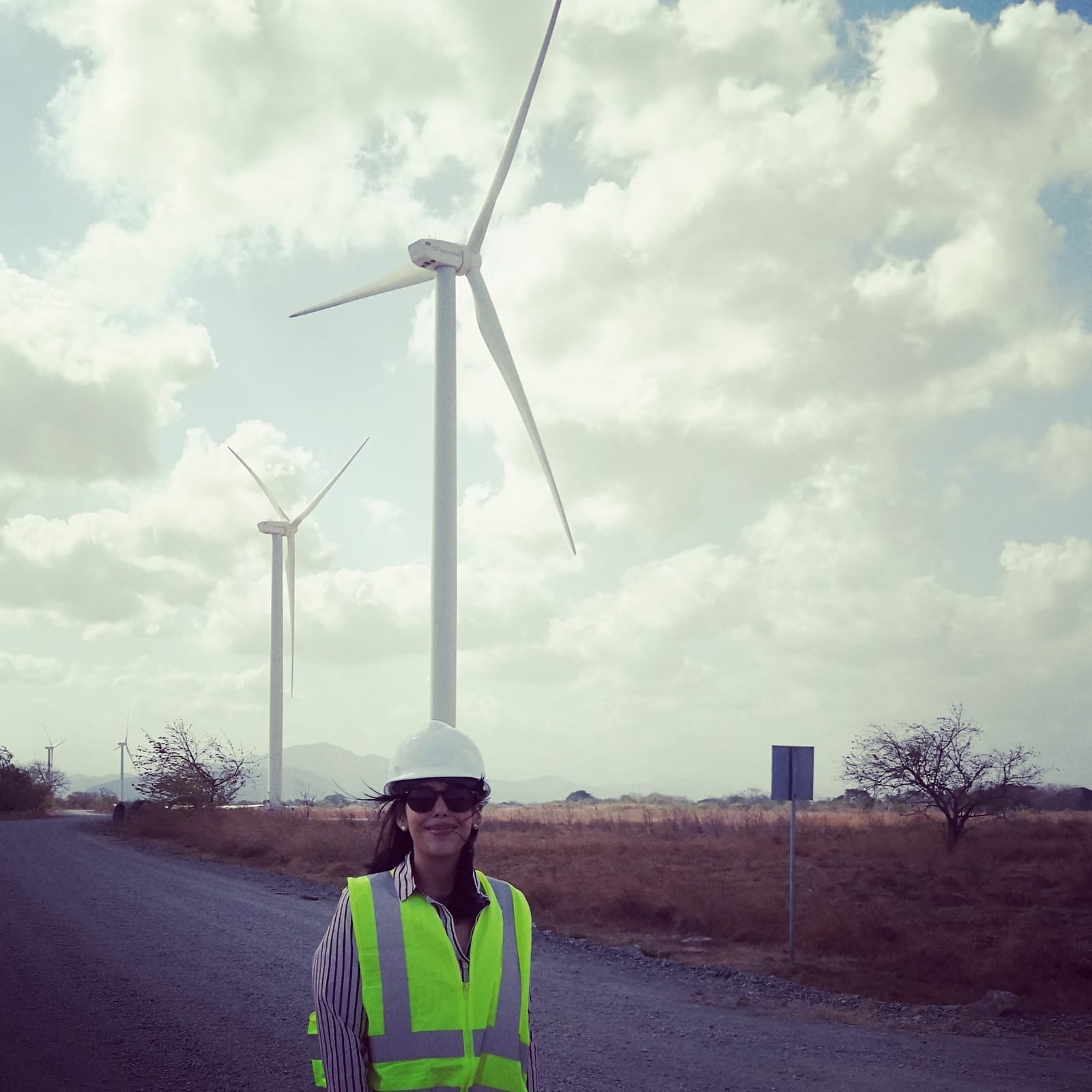 Woman stands in front of wind turbine